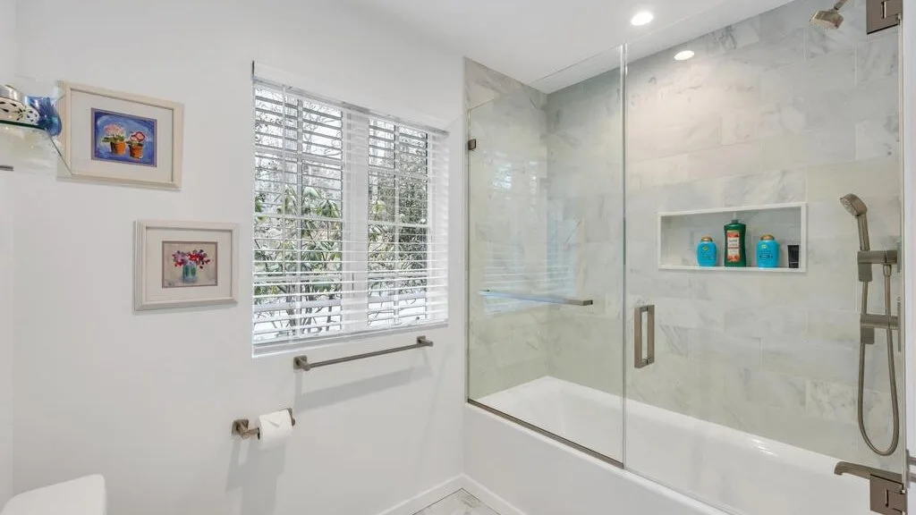 Un baño con ducha de cristal, bañera y ventana.