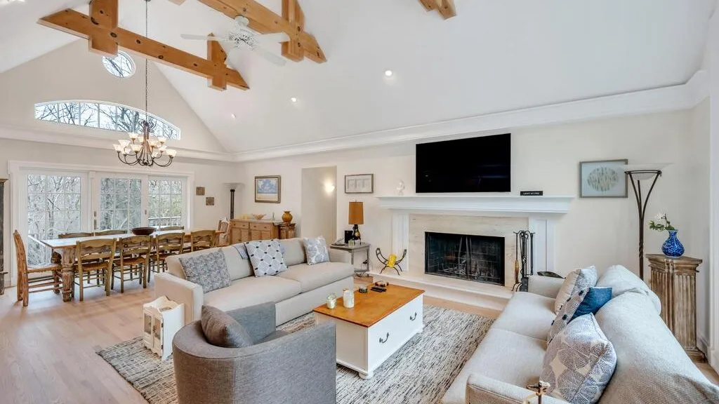 A bright living room with a fireplace, seating, and a dining area.
