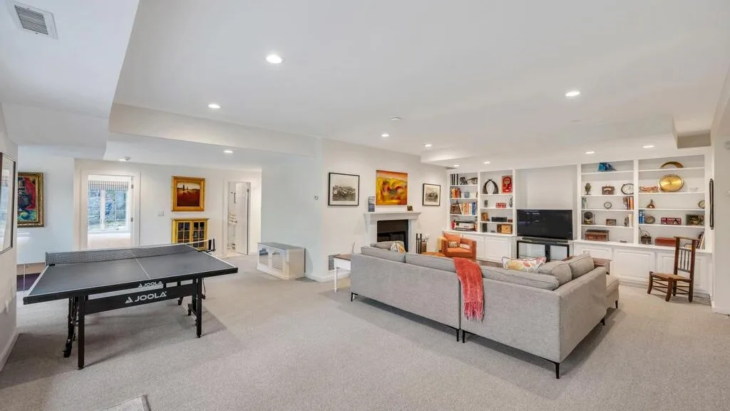 Una sala luminosa con zona de asientos, televisor y mesa de ping-pong.