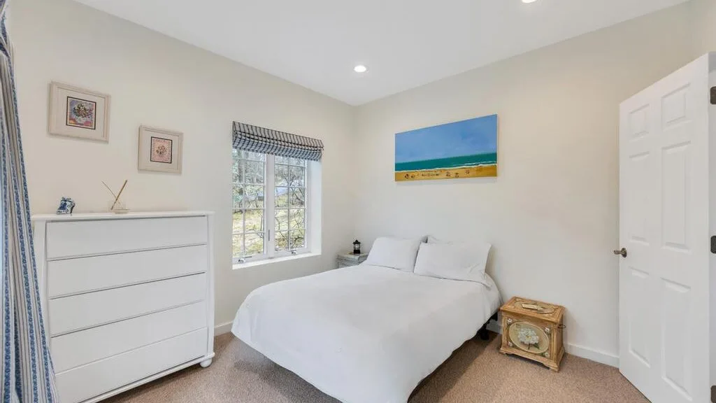Un dormitorio luminoso con una cama, una cómoda y una ventana.