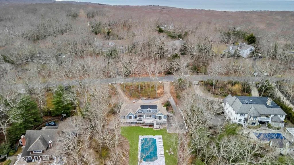 Una vista aérea muestra varias casas rodeadas de árboles y una piscina detrás de la casa central.