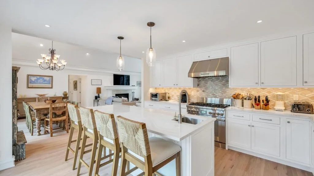 Una cocina y comedor abiertos y luminosos, con una isla grande y asientos de madera.