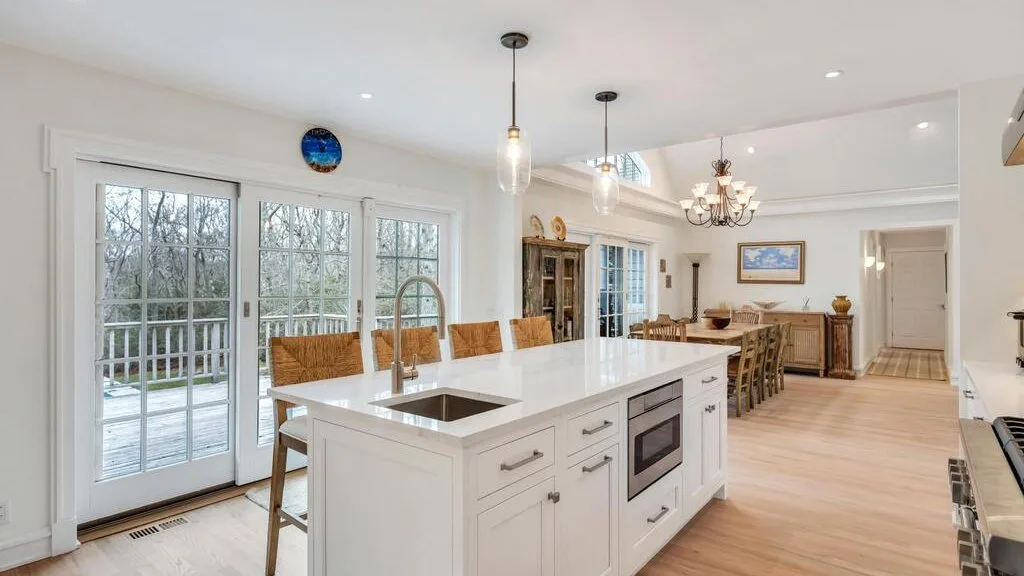 Una cocina luminosa cuenta con una gran isla blanca y una mesa de comedor.