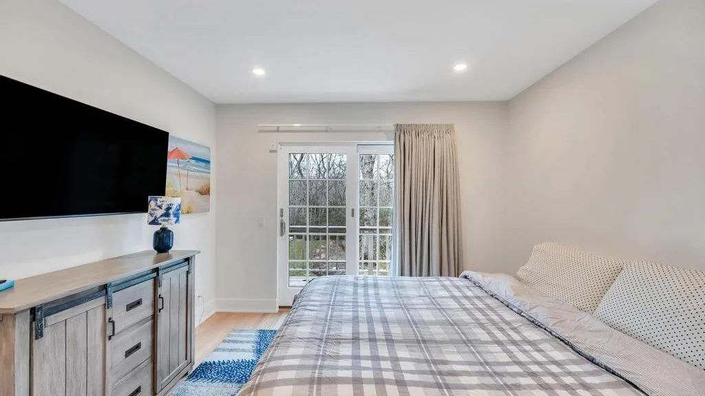 Un dormitorio con una cama grande, un televisor y puertas de vidrio que dan a un patio.
