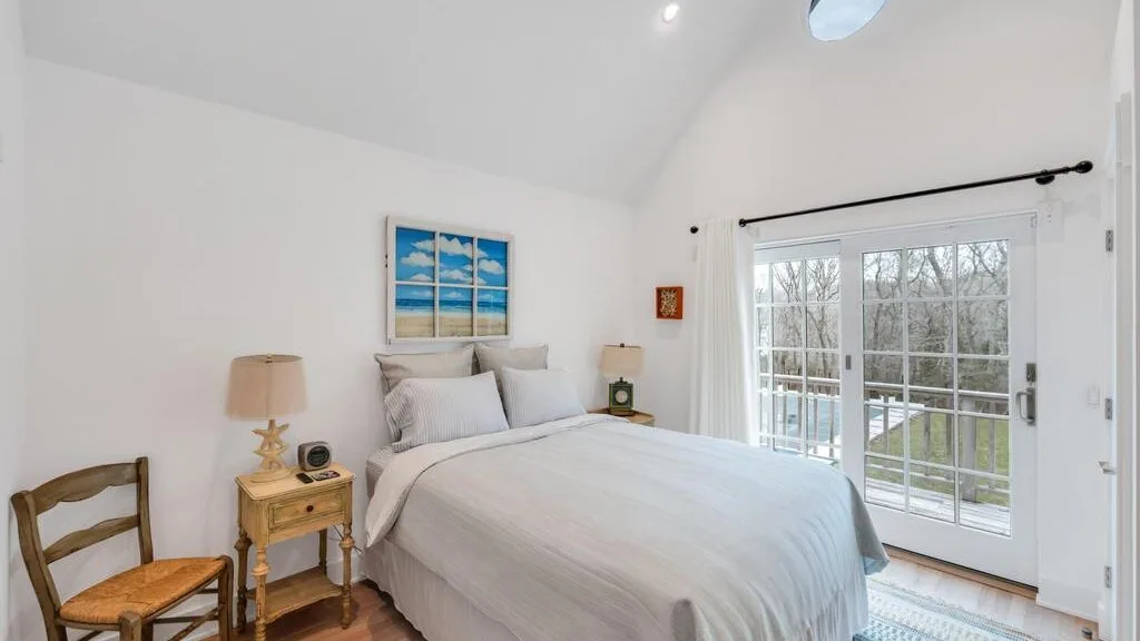 Un dormitorio luminoso con una cama junto a grandes puertas de vidrio que dan a un patio.