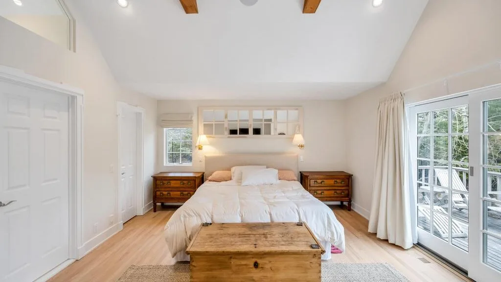 Un dormitorio luminoso con una cama entre dos mesas de noche de madera.