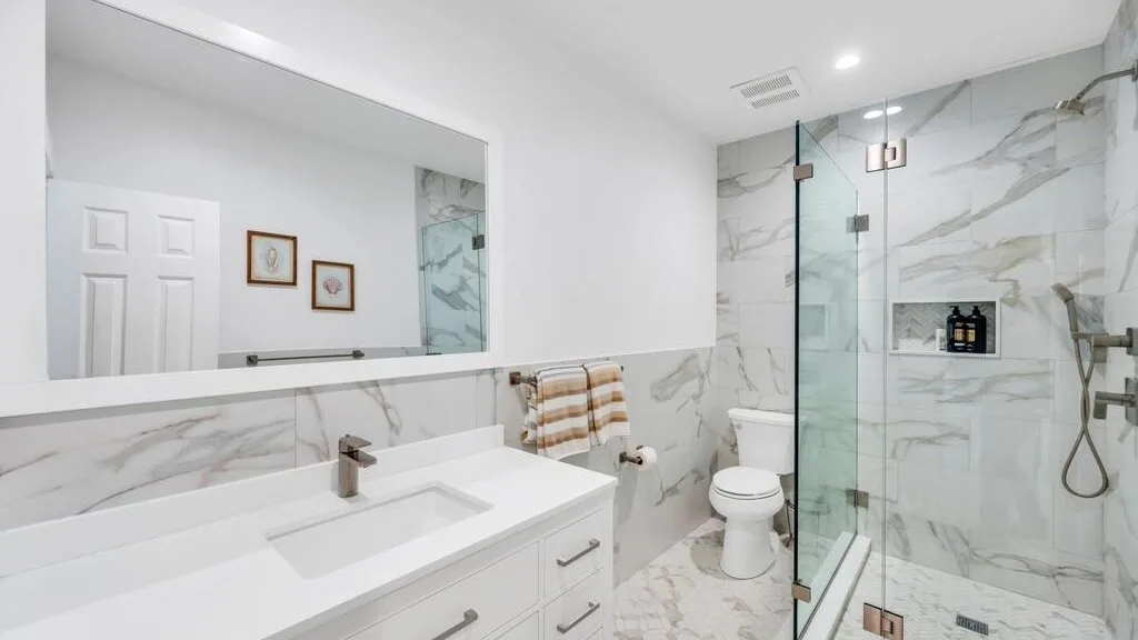 Un baño luminoso con un amplio tocador y una ducha de vidrio.
