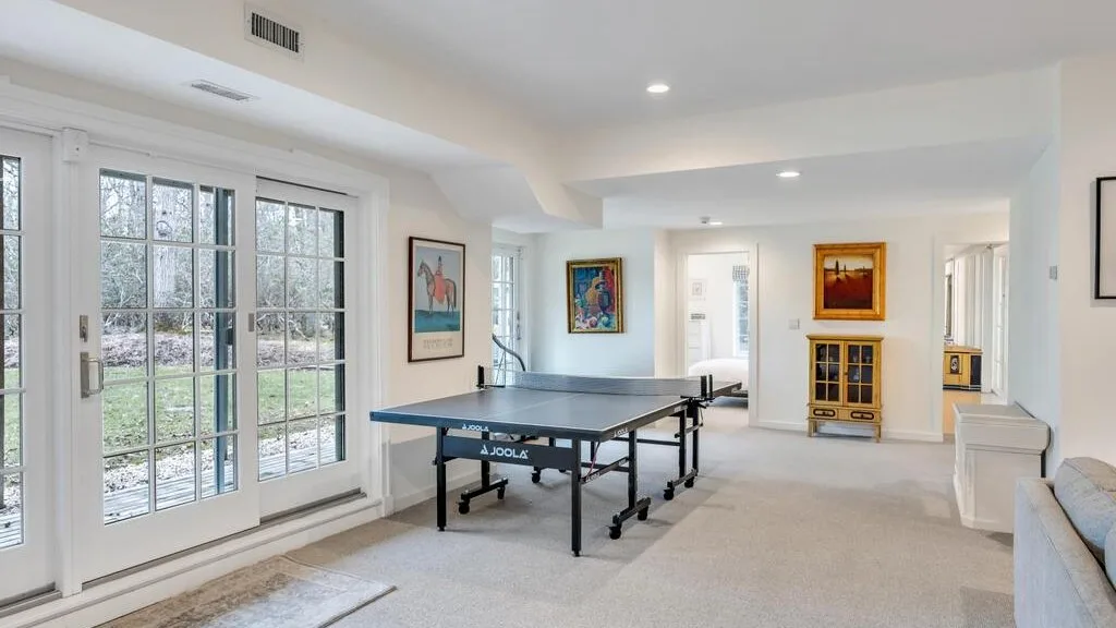 Un luminoso salón de juegos con una mesa de ping-pong junto a grandes ventanas.