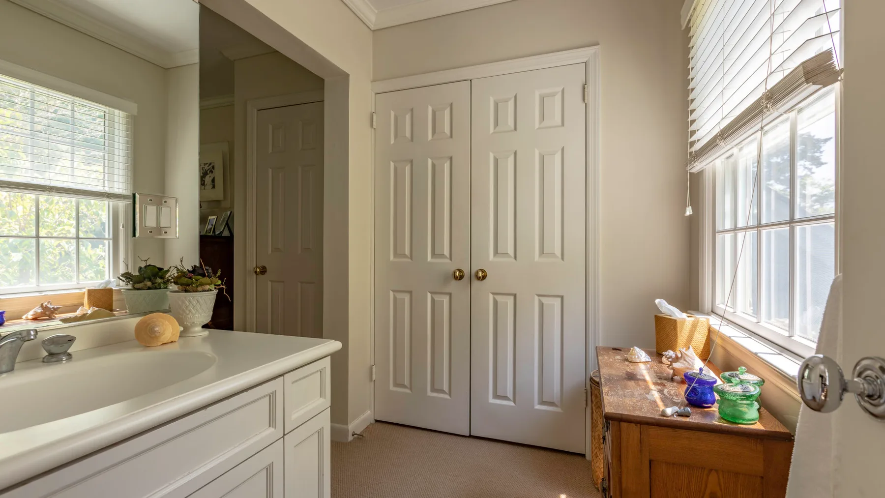 Un tocador de baño está junto a una bañera, con un mueble de madera bajo la ventana.