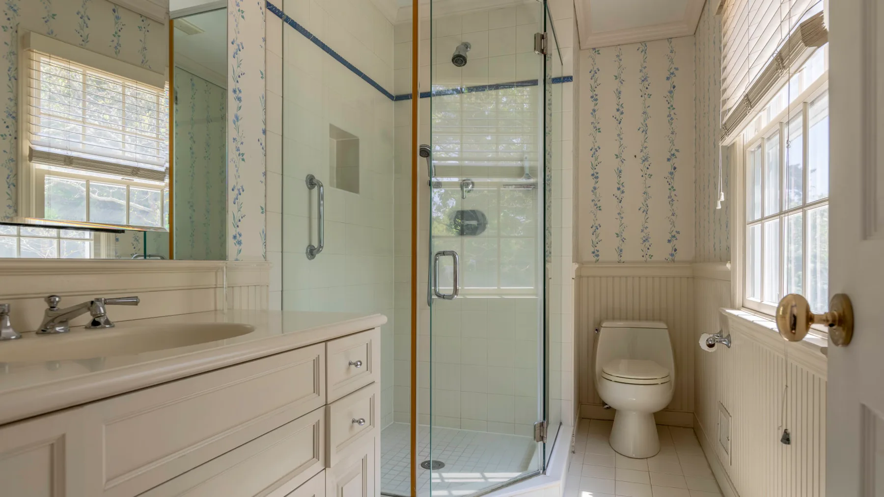 Un baño luminoso con ducha de vidrio, lavabo y sanitario.