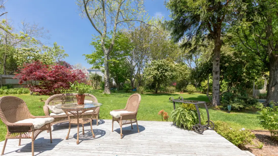 Un patio de jardín con asientos y una mesa da a un césped verde.