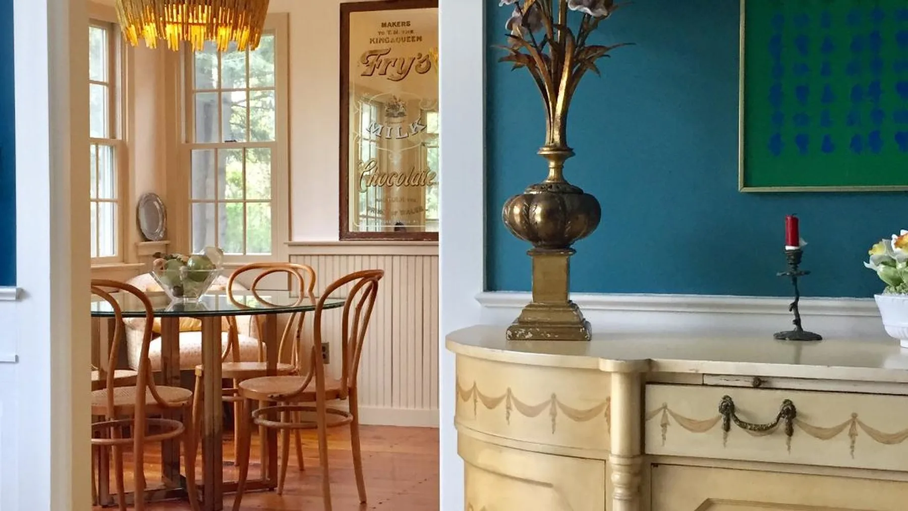 Un comedor con una mesa y sillas de madera junto a una sala con paredes verde azulado.