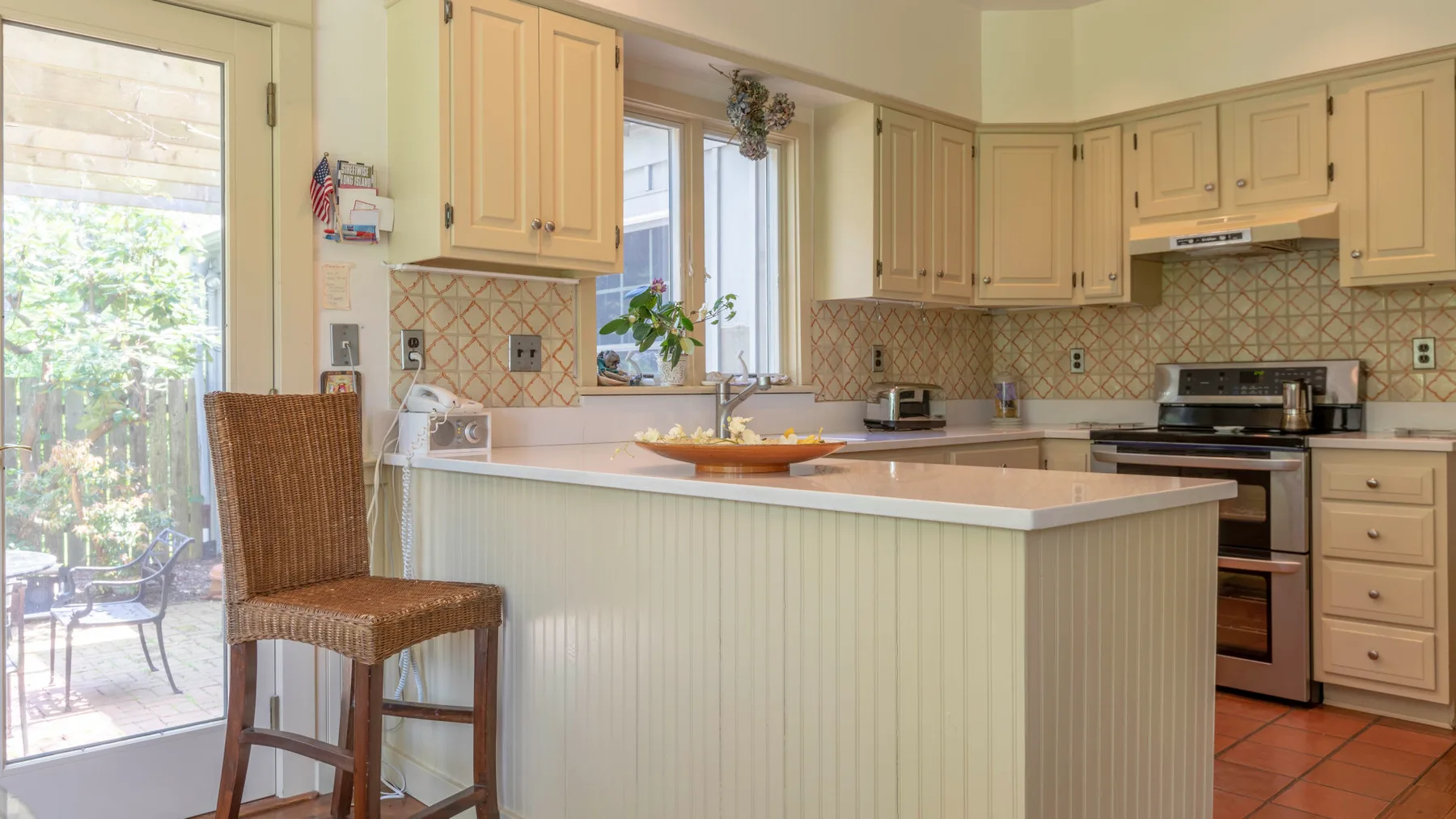 Una cocina luminosa con gabinetes claros, un salpicadero de azulejos y una encimera.