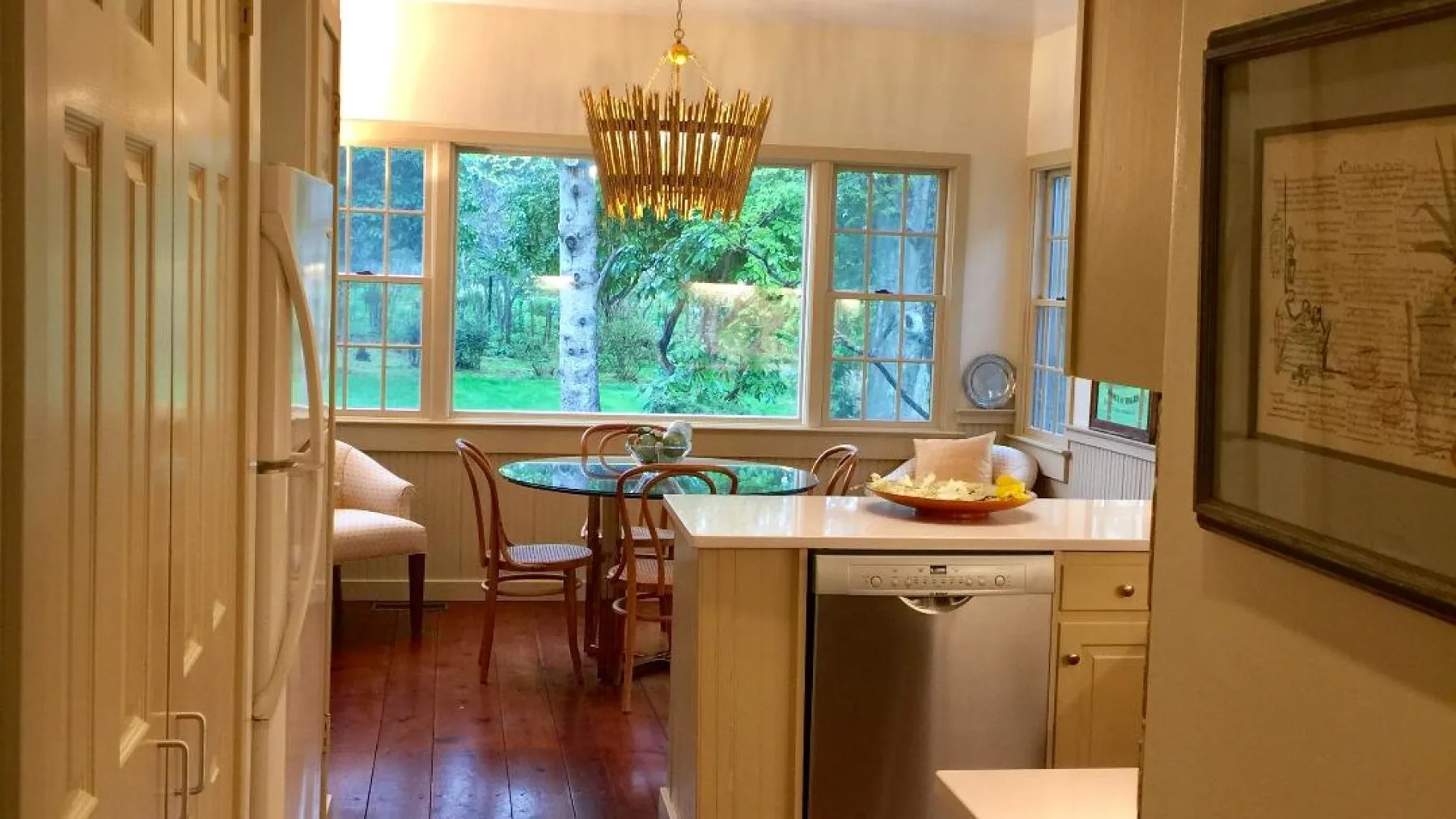 Una cocina y comedor luminosos con una mesa junto a grandes ventanas.