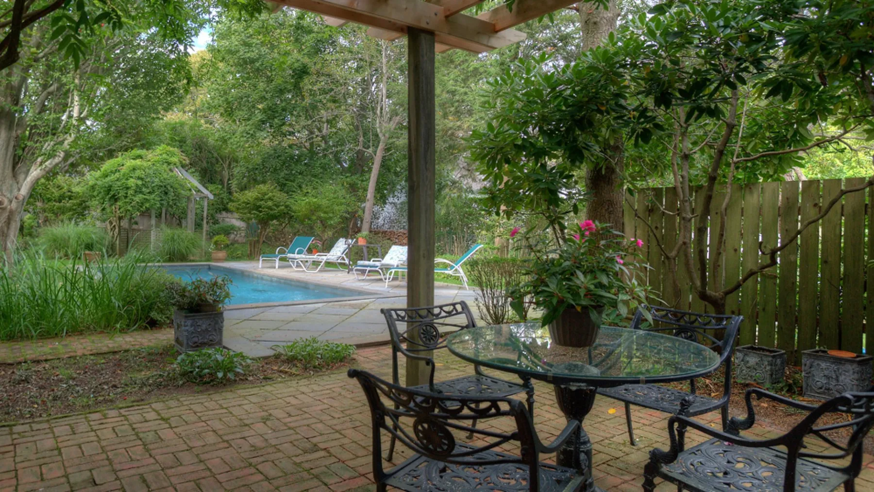 Un patio ajardinado con asientos al aire libre da a una piscina.