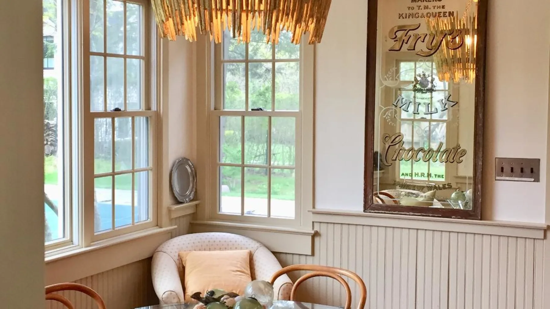 Una luminosa zona de estar tiene ventanas altas, un asiento acolchado y una lámpara colgante.