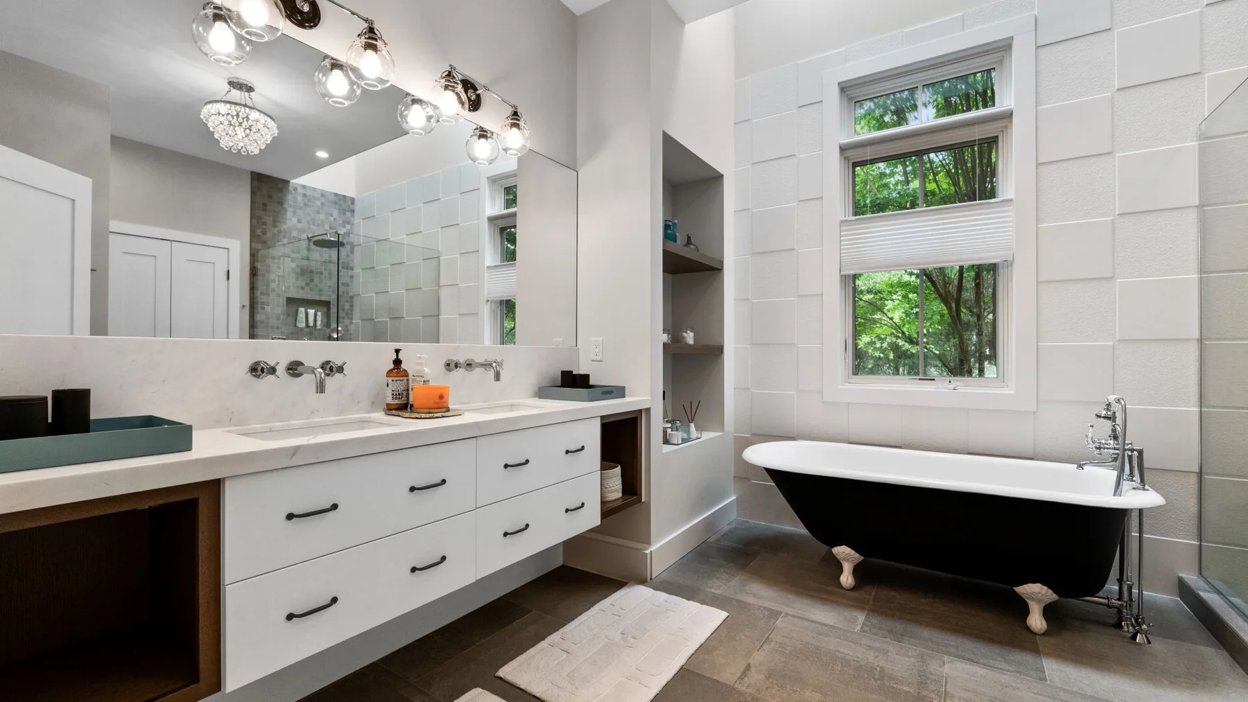 A bright bathroom features a long vanity, a large mirror, and a freestanding bathtub.