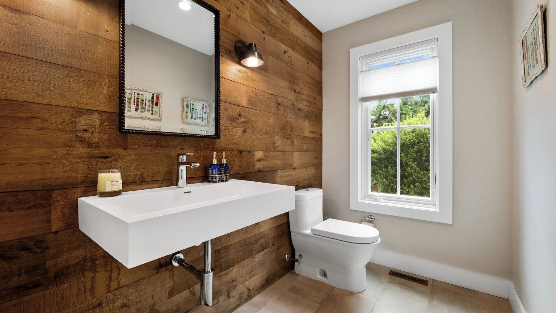 A bathroom with a floating sink, toilet, and window.