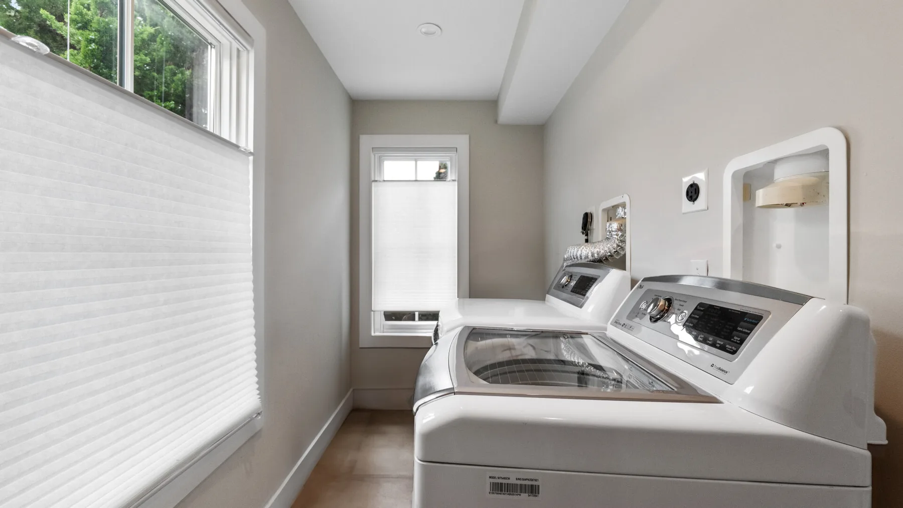 A laundry room with a washer and dryer beneath the windows.