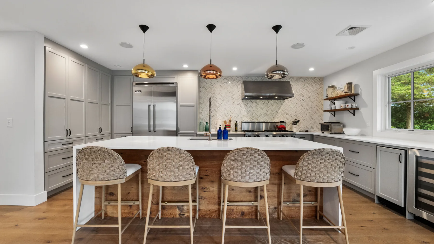 A bright kitchen with a central island and four bar stools.