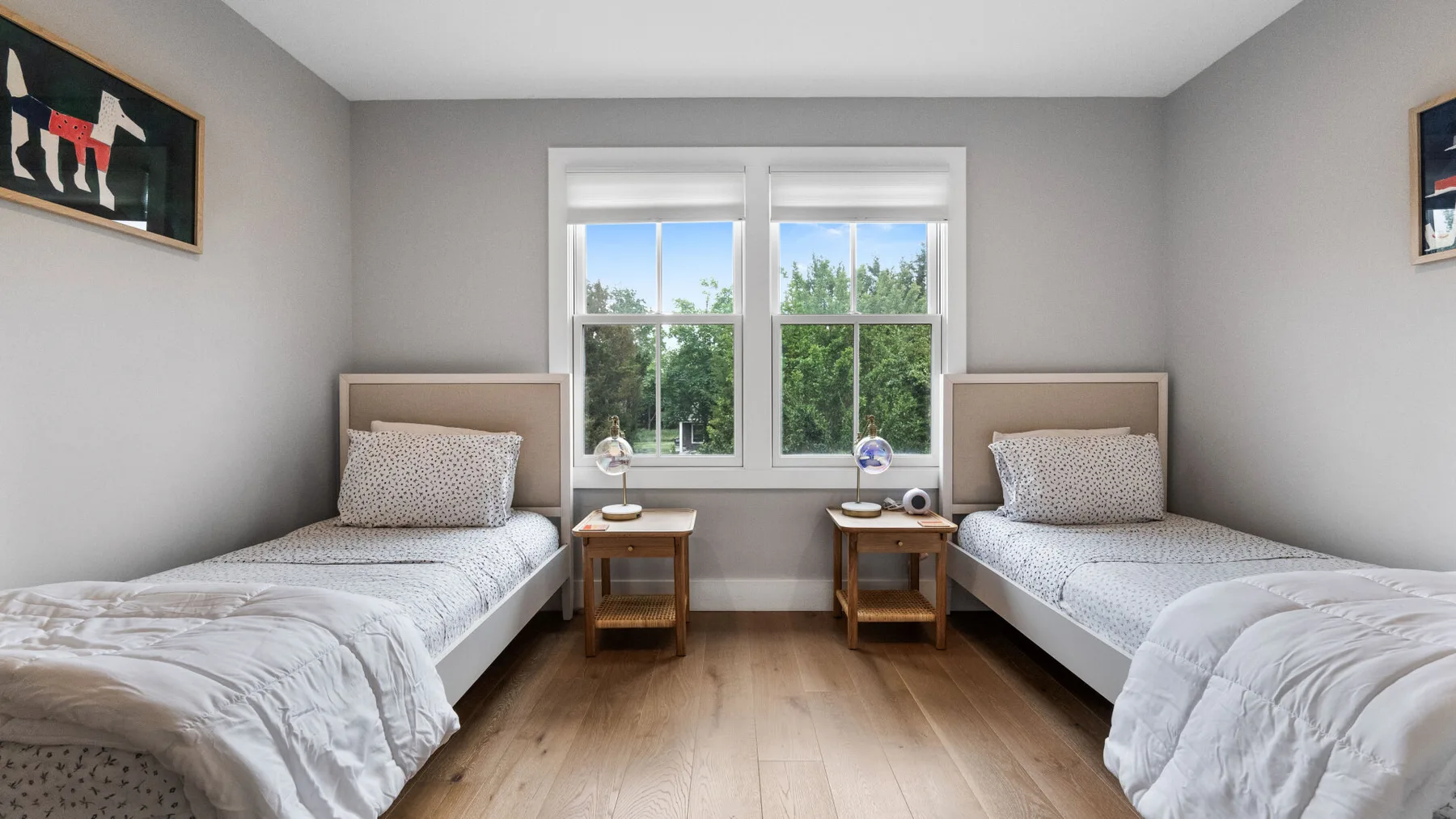 A bedroom with two single beds beside a large window.
