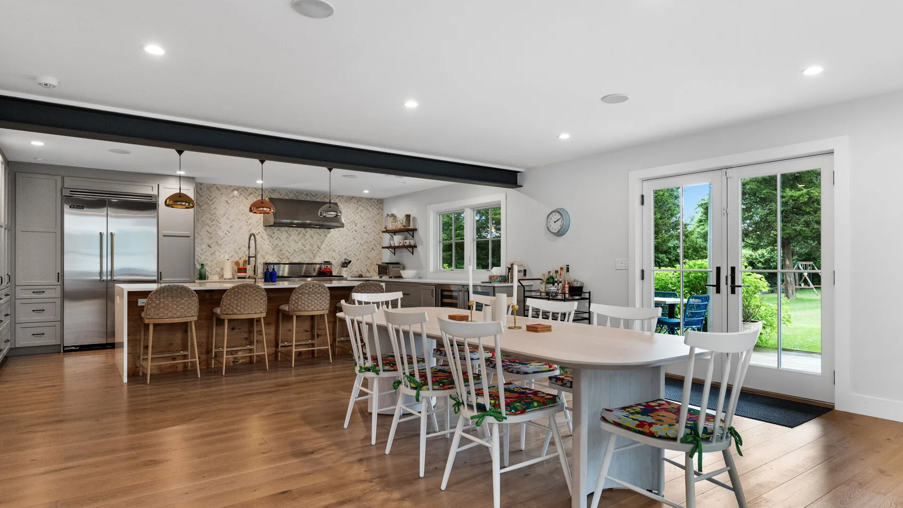 Una luminosa cocina-comedor diáfana con una mesa larga y puertas que dan al jardín.