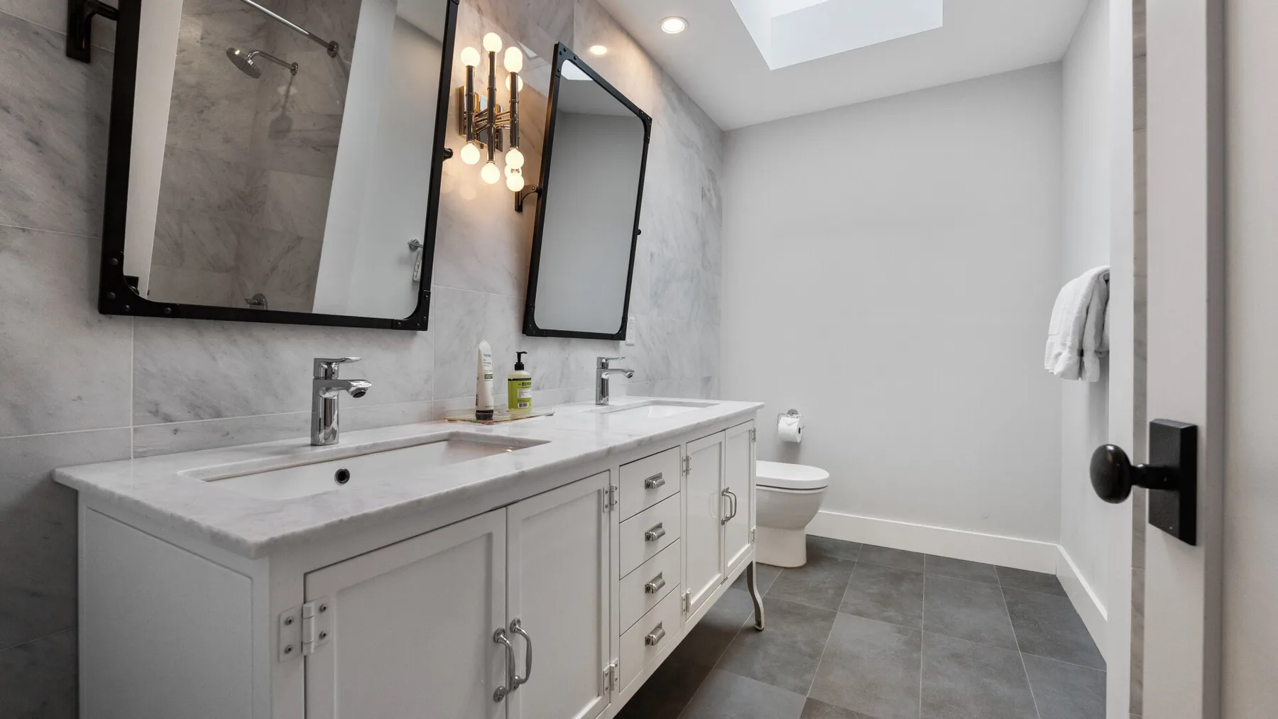 A bright bathroom with a double vanity and a shower.