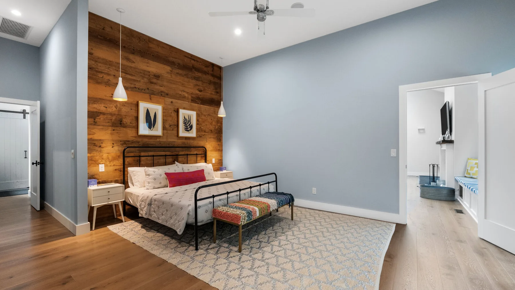 A bedroom with a bed against a wood-paneled accent wall and a bench at its foot.