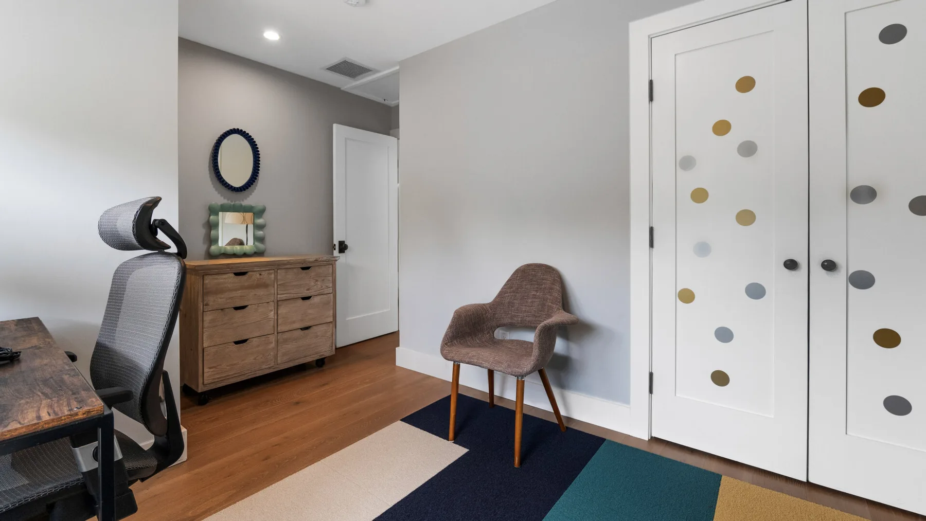 A home office with a desk, wooden dresser, and upholstered seating.