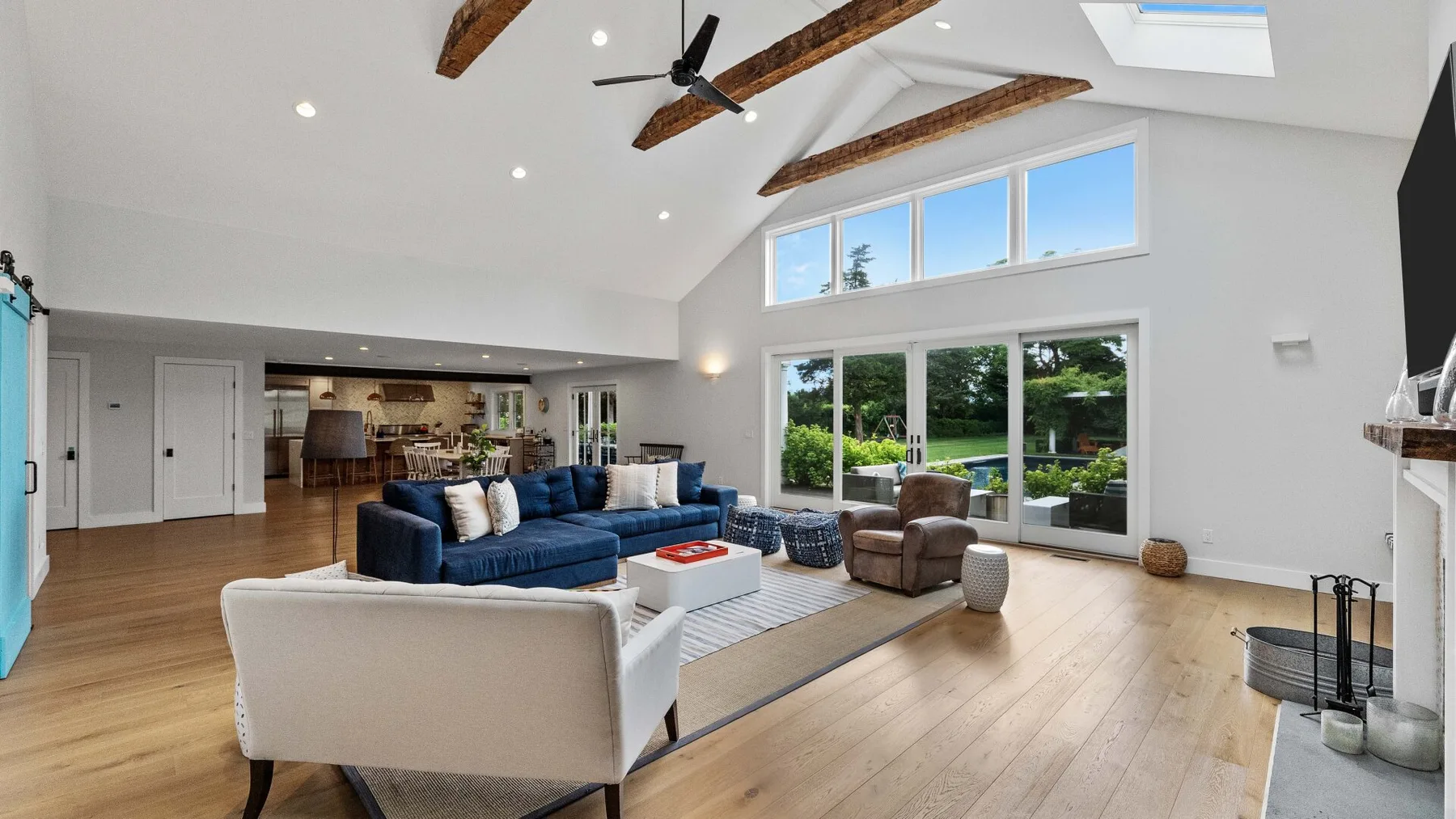 A spacious living room with seating, large windows, and exposed ceiling beams.