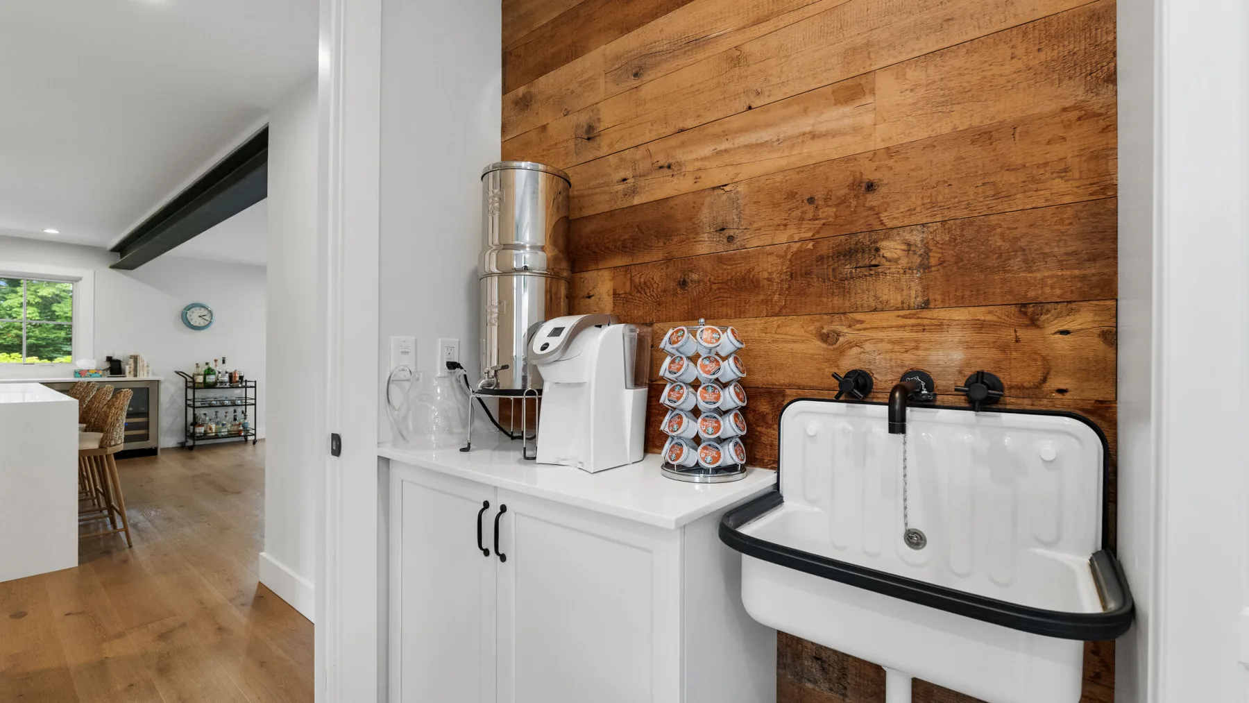 A beverage station with a white sink sits against a wood-paneled wall.