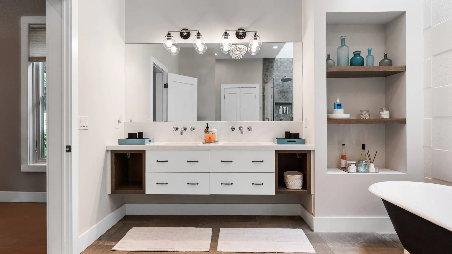 A bright bathroom vanity with a wide mirror and open shelving.