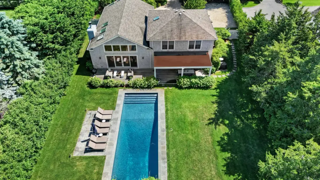 Aerial view of a house with a rectangular swimming pool in the lawn.