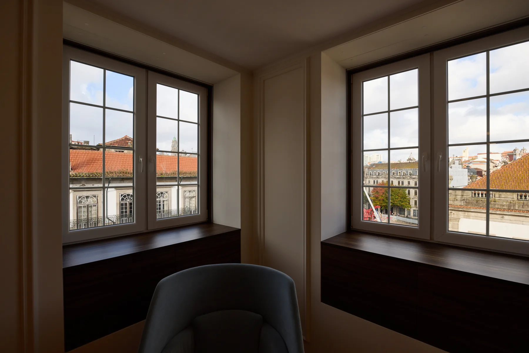 A bright window nook overlooks nearby rooftops and city buildings.