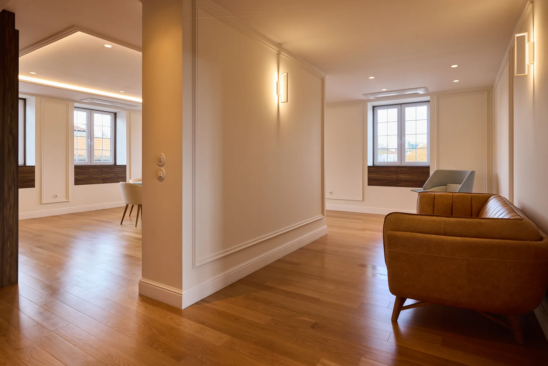 A bright living room with wood flooring and seating beside a window.