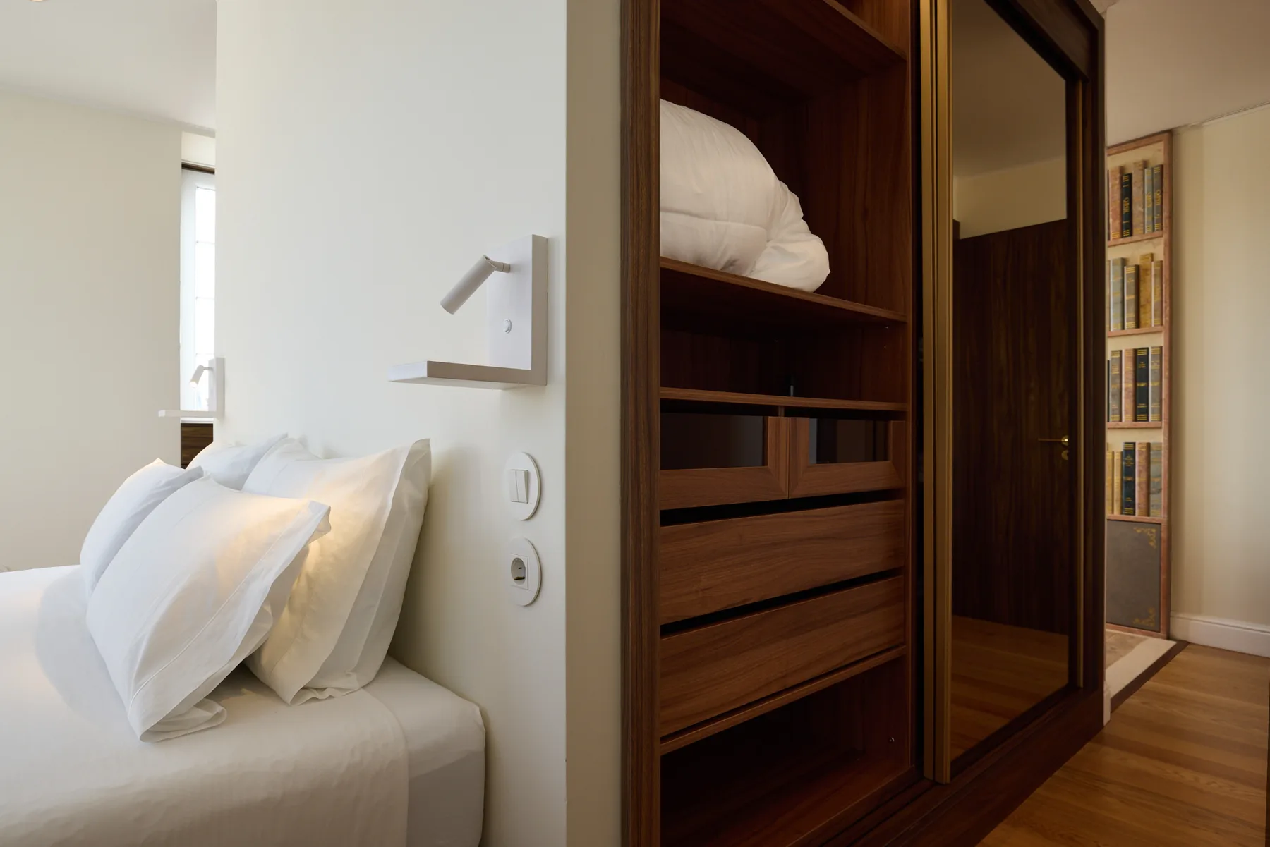 A bedroom with a bed beside a dark wooden wardrobe.