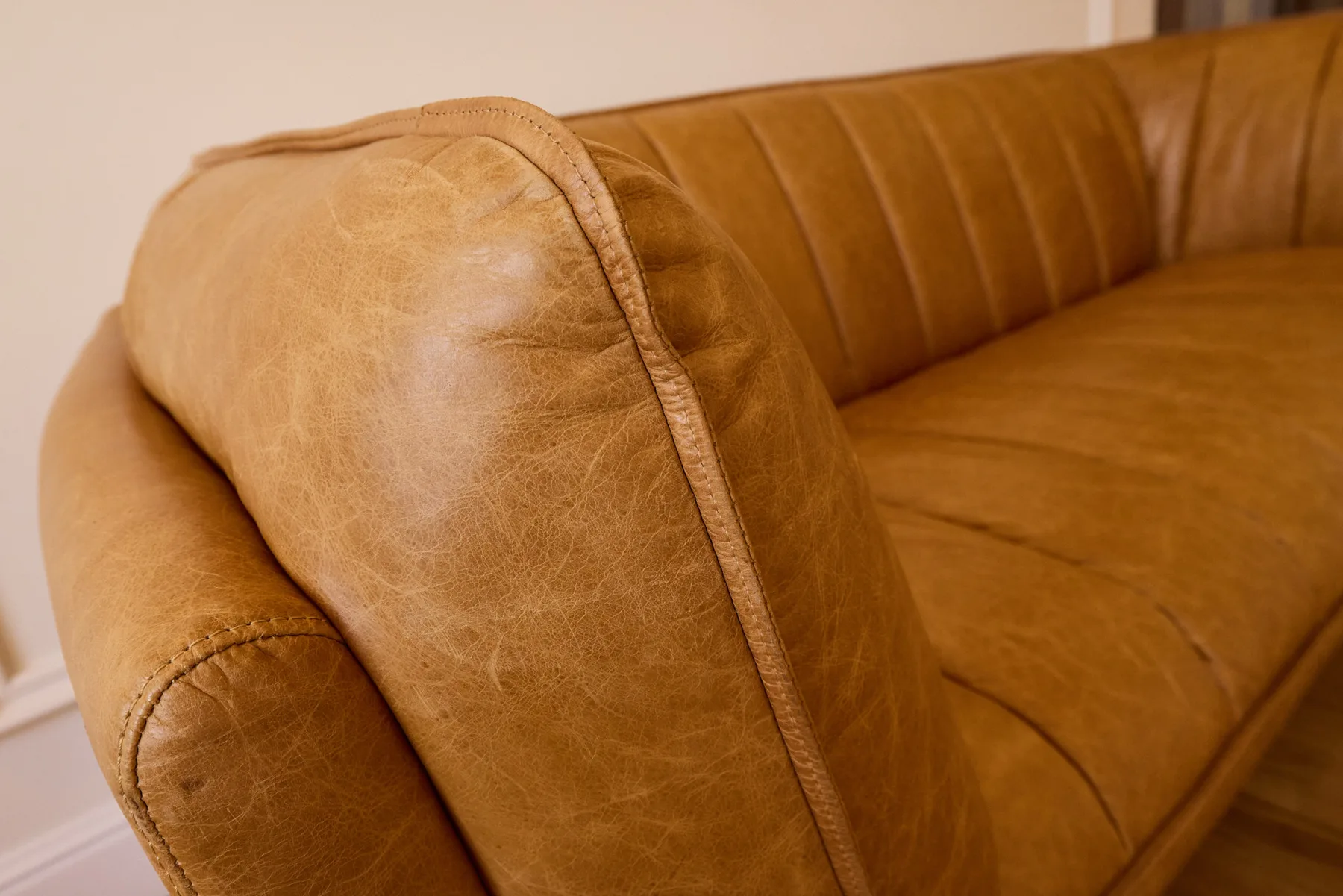 Close-up of a tan leather sofa with visible stitched seams.