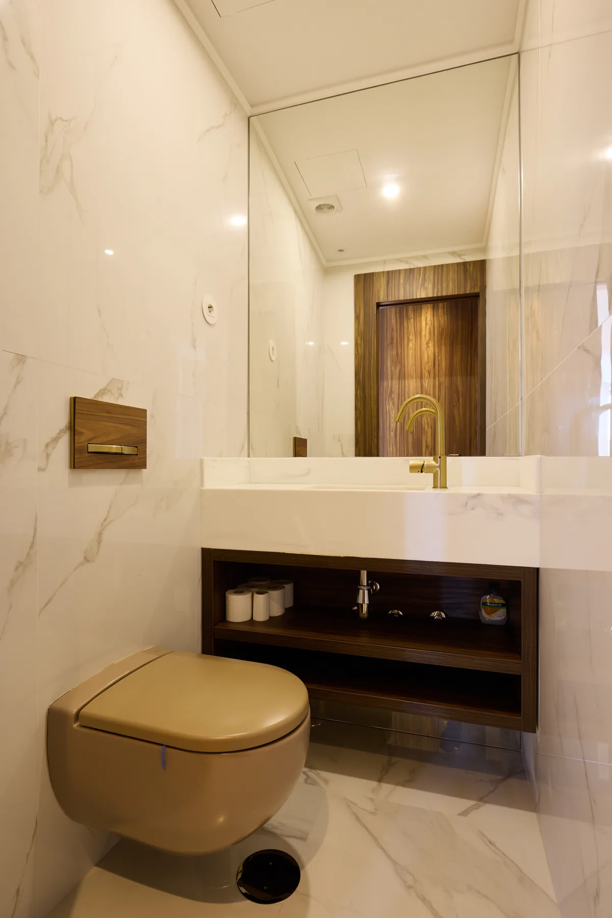 A modern bathroom with a wall-mounted toilet, floating vanity, and large mirror.