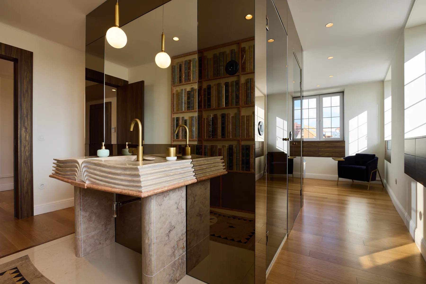A bright bathroom vanity opens onto a living area with large windows.