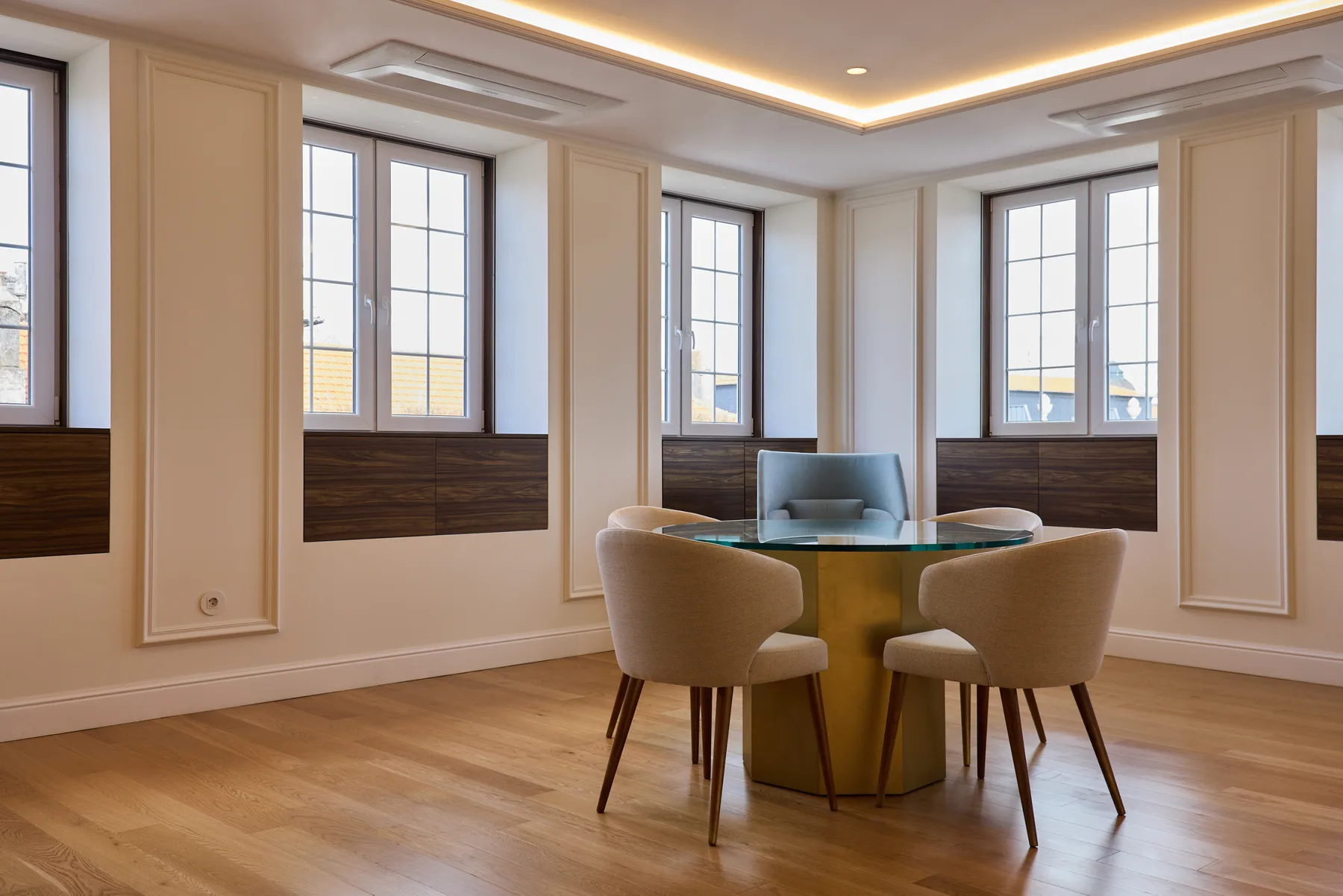 A bright sitting area with a round table and chairs beside several windows.