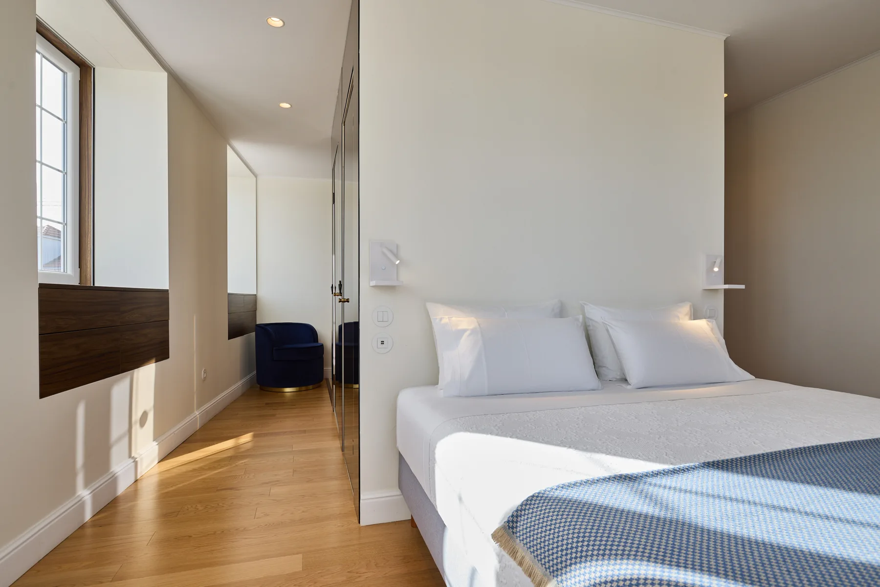 A bedroom with a neatly made bed and a narrow passage beside it.