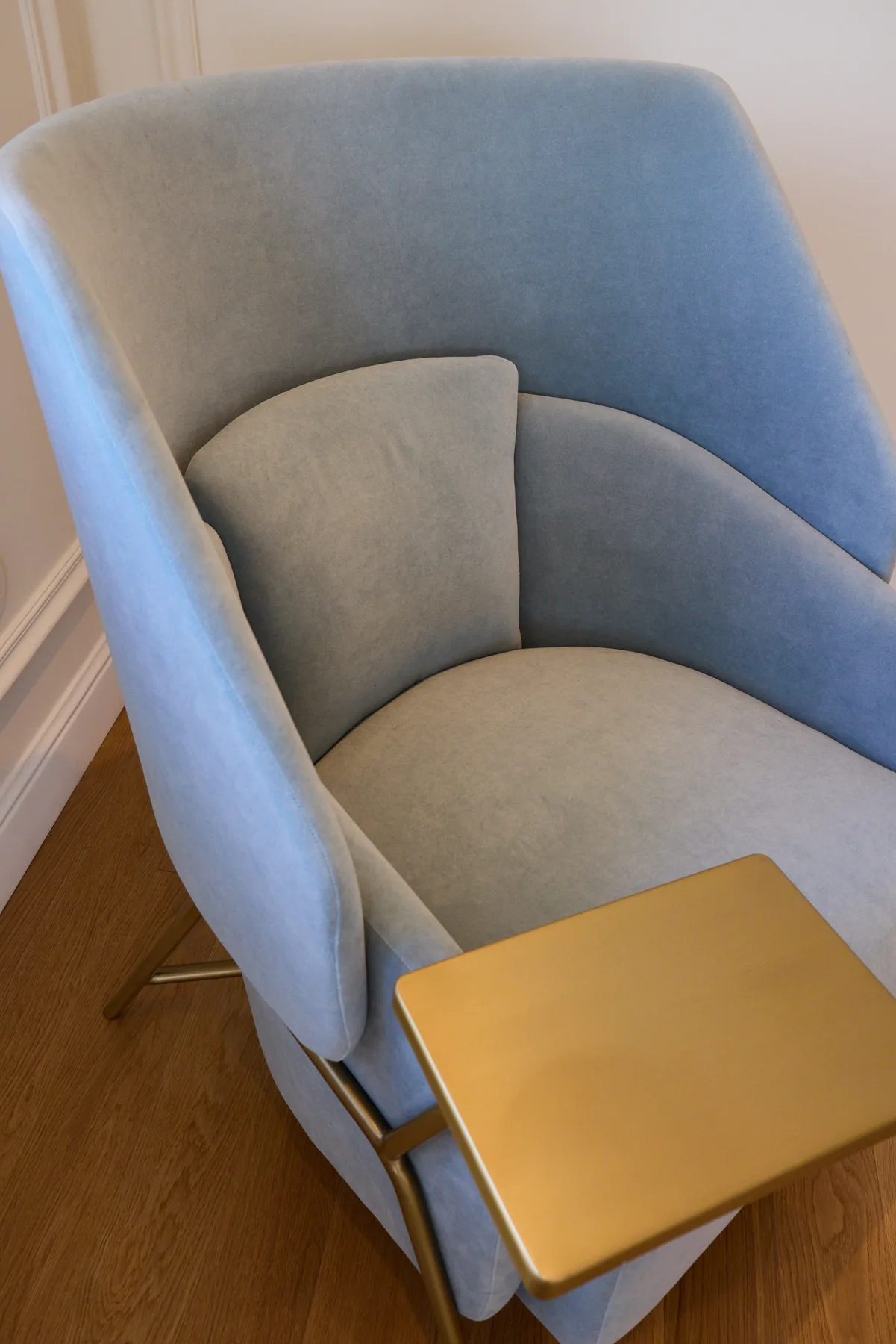 A blue upholstered armchair sits beside a small gold-colored table.