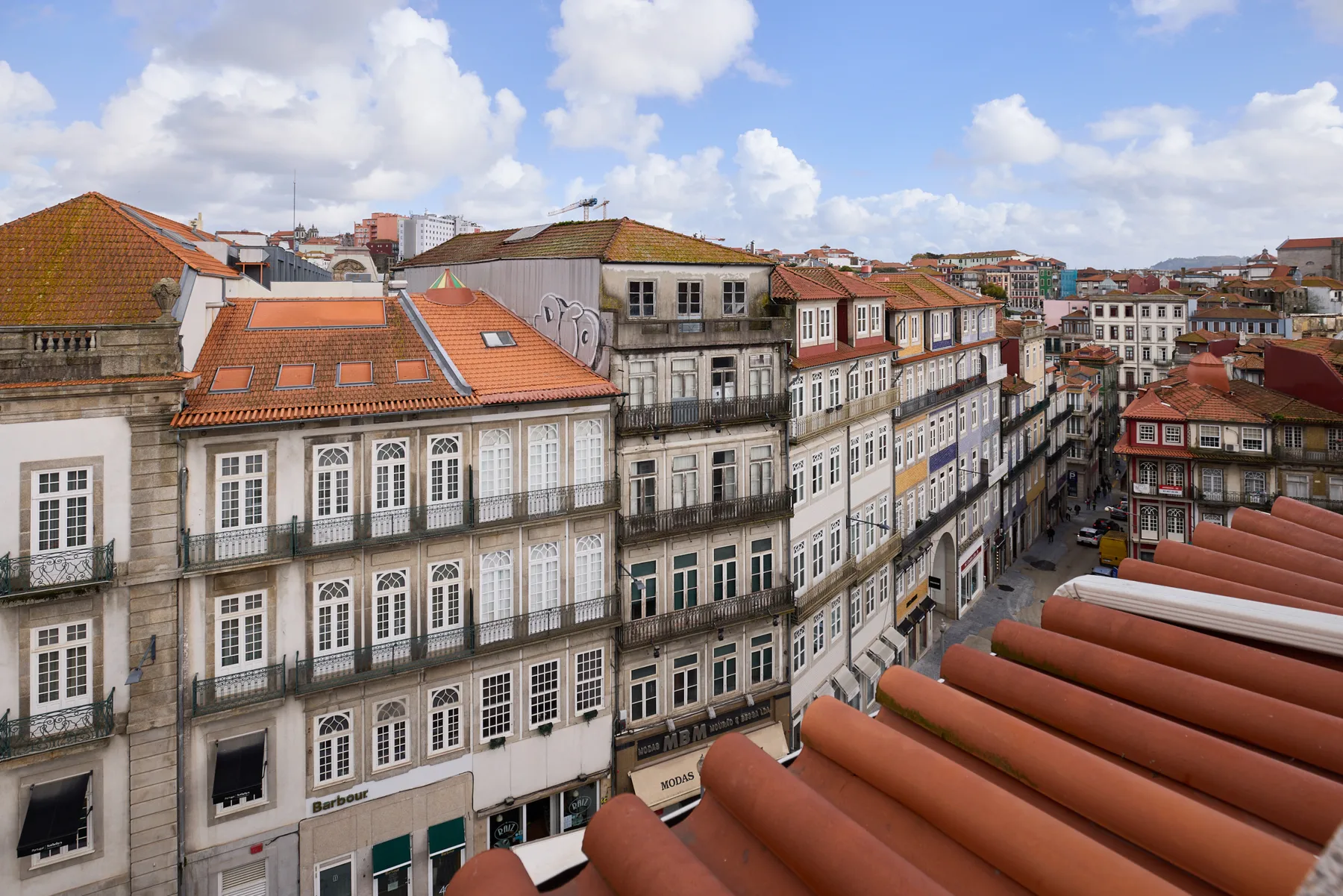 A cityscape of Porto rooftops and closely packed historic buildings beneath a cloudy sky.