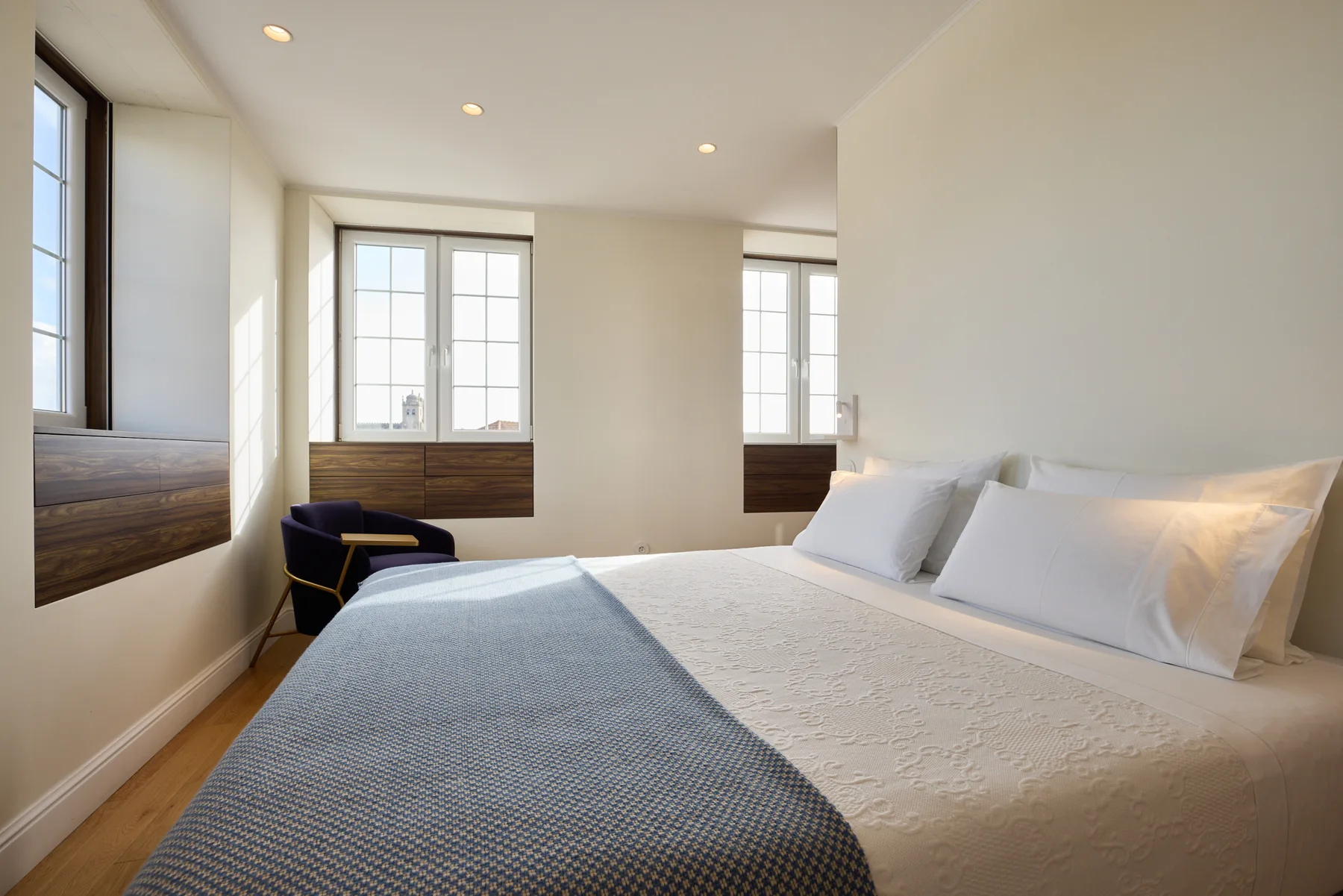A bright bedroom with a bed beneath several tall windows.