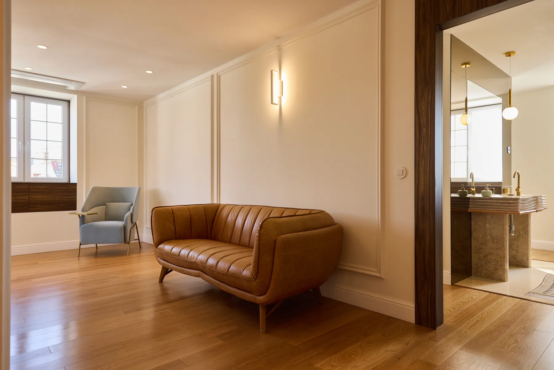 A living room with brown seating and a doorway opening onto a bathroom.