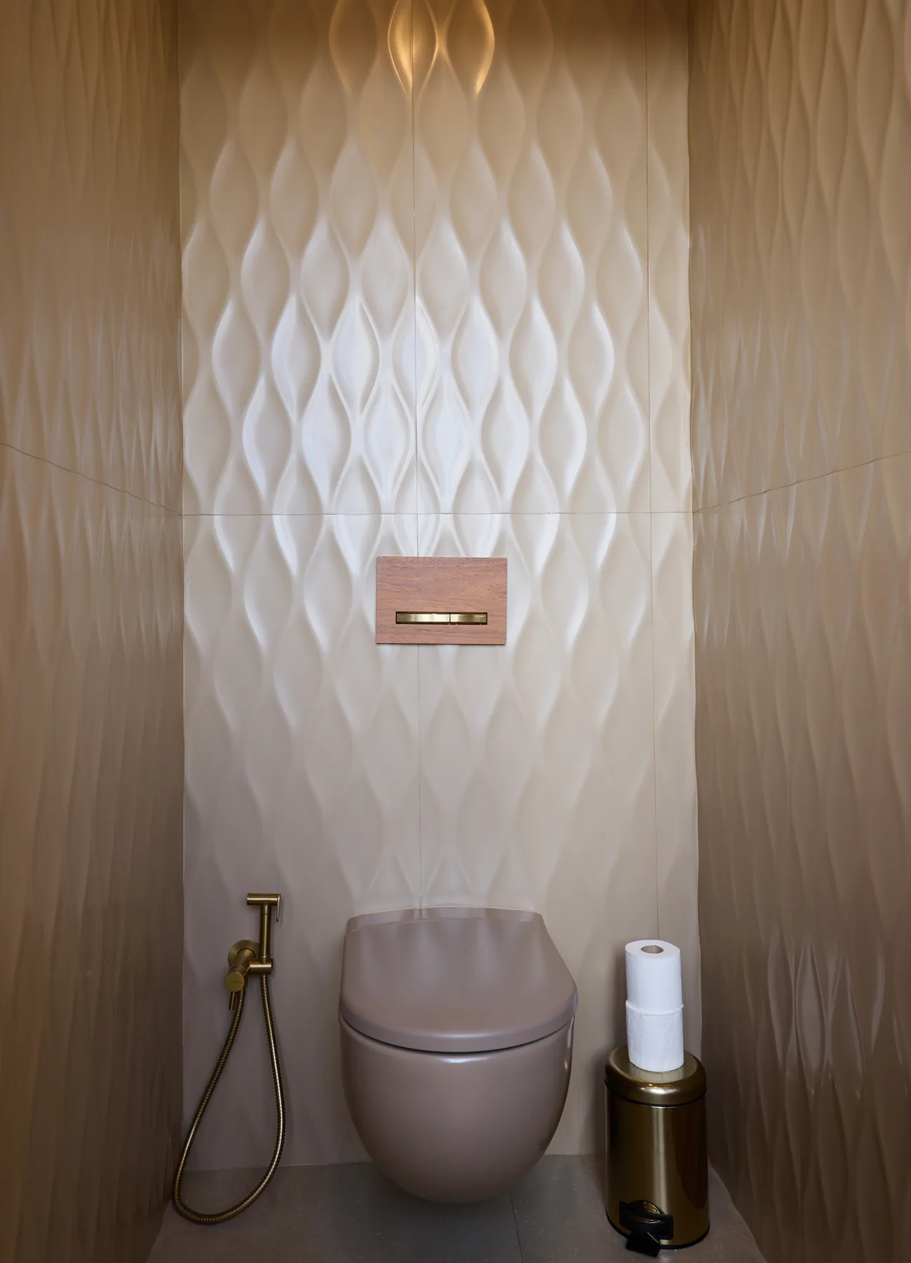 A modern bathroom features a wall-mounted toilet against a textured wall.