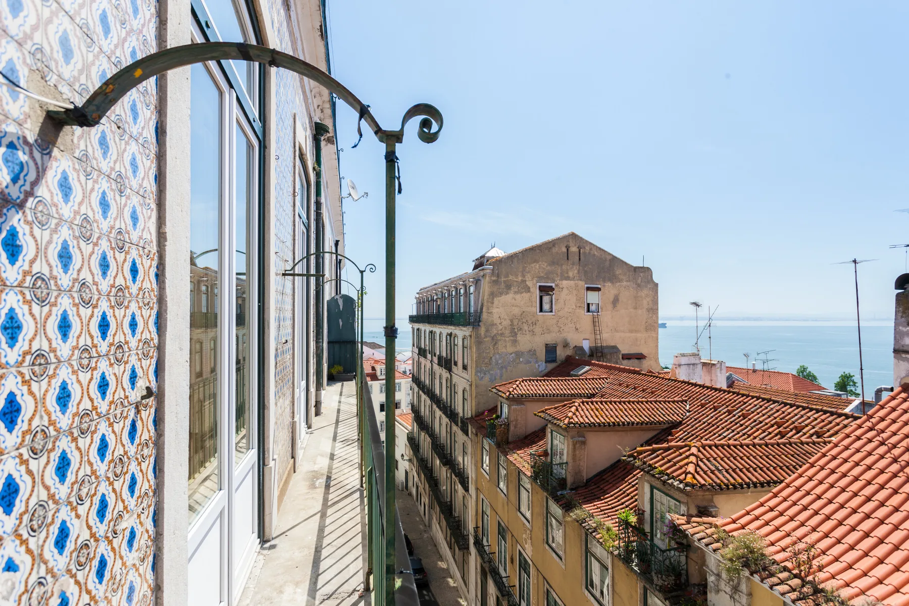 A narrow balcony overlooks tiled rooftops and the sea.