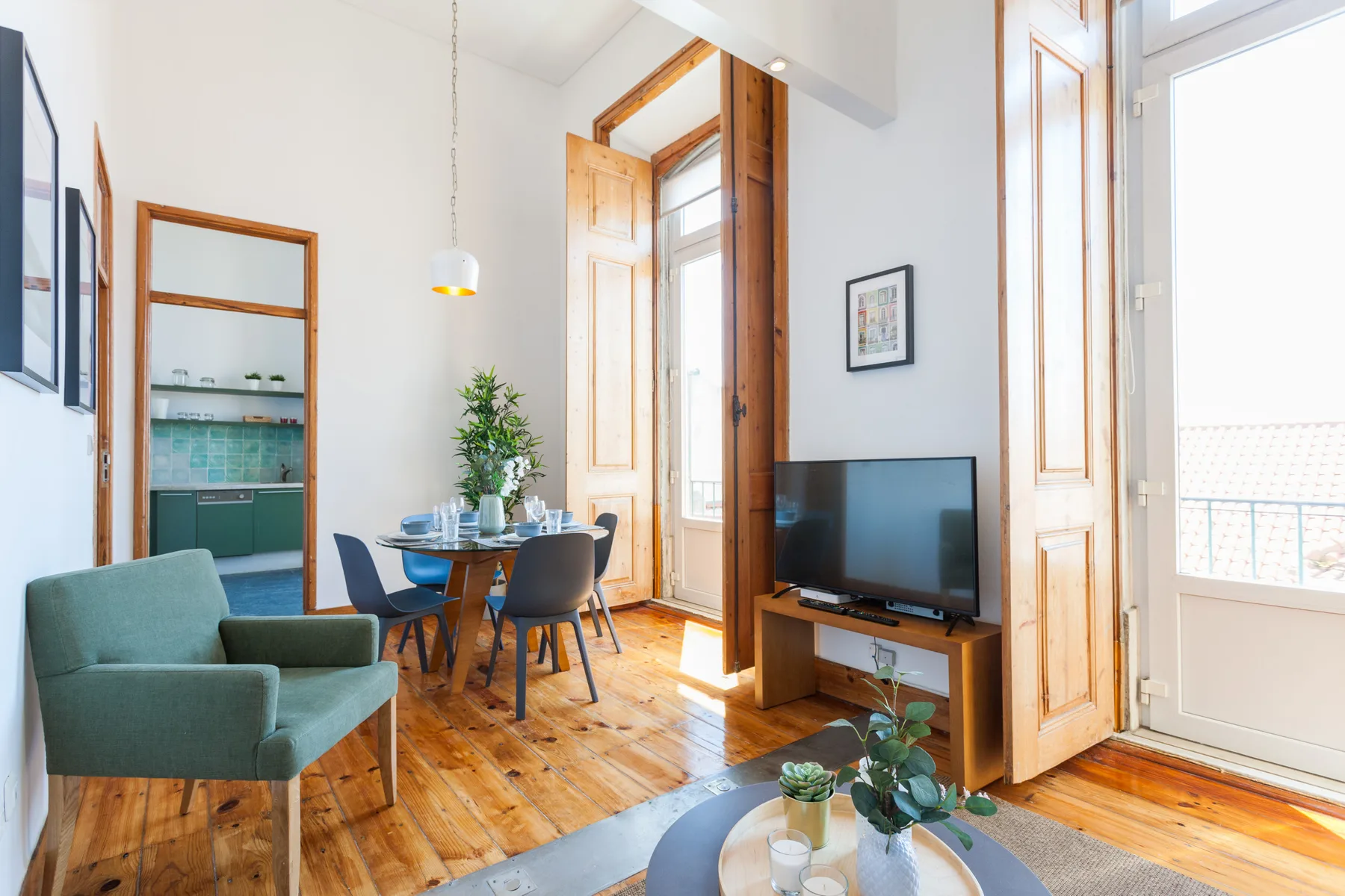 A bright living and dining area with seating, a table, and a television.