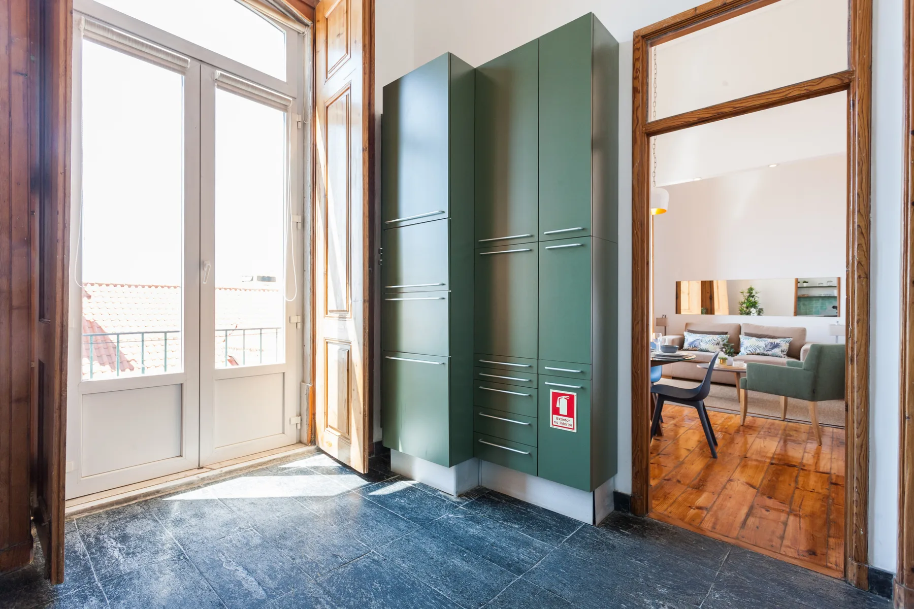 A bright entryway with tall green cabinets and an open doorway to a living area.