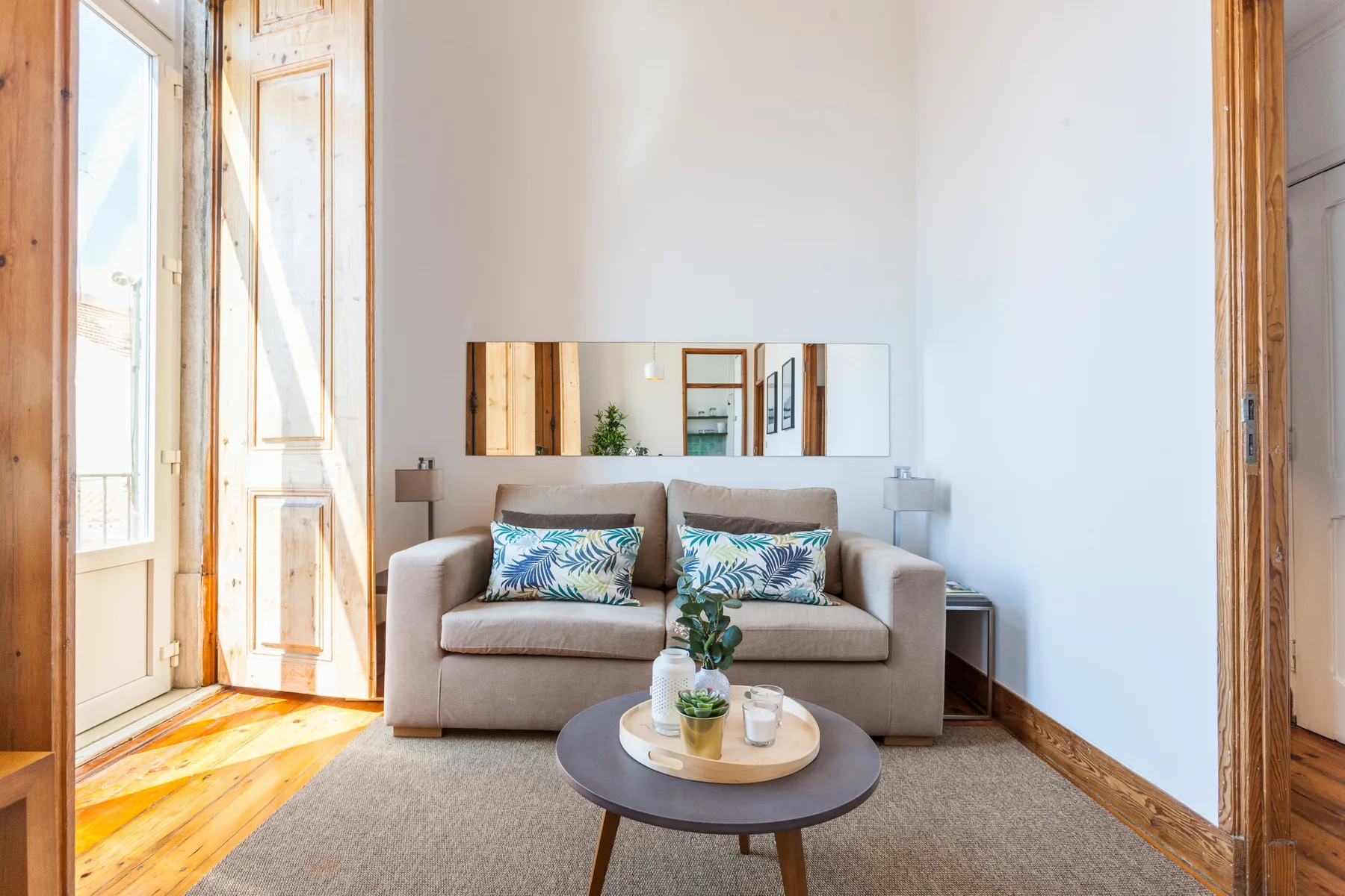 A bright living room with a sofa, coffee table, and tall windows.